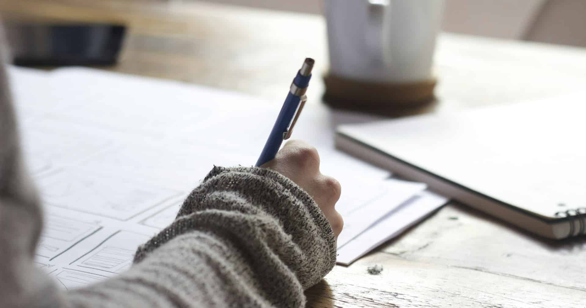 Person writing focused notes — representing the craft of writing effective Claude AI prompts