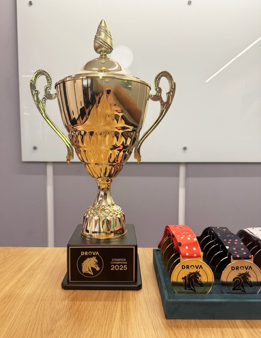 Gold Drova Stampede Champions trophy with an engraved 2025 plaque, medals in a tray beside it